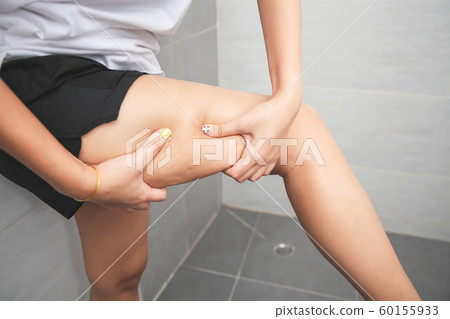 Woman pinching her leg and showing cellulite in 60155933