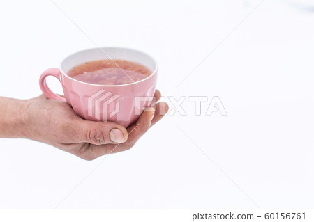 Hand holds a pink mug with a drink on a background 60156761
