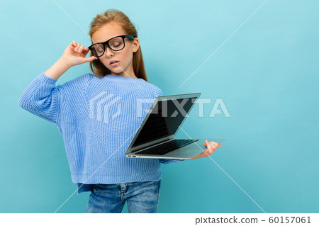 attractive european girl holding a computer in her hands with the screen forward on a light blue 60157061