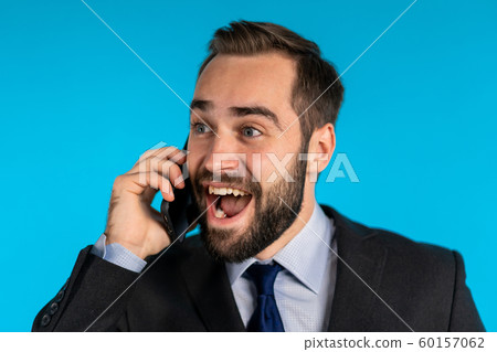 Surprised excited happy businessman talking on mobile telephone on blue background. Man saying wow. 60157062