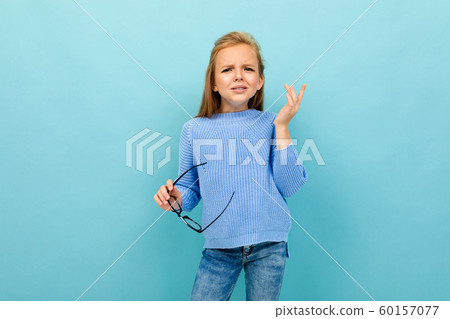 beautiful european girl squints with glasses in hand on light blue wall beautiful european girl squints with glasses in hand on light blue wall 60157077