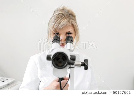 Female blond doctor gynecologist looks through a 60157661