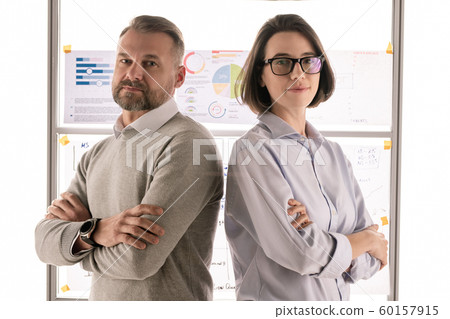 Two successful economists with crossed arms standing in front of camera Two successful economists with crossed arms standing in front of camera 60157915