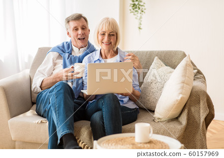 Senior couple using laptop, watching video or shopping online Senior couple using laptop, watching video or shopping online 60157969