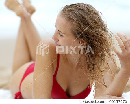 Sexy woman in a bikini relaxes on a sandy beach at the ocean Sexy woman in a bikini relaxes on a sandy beach at the ocean 60157970