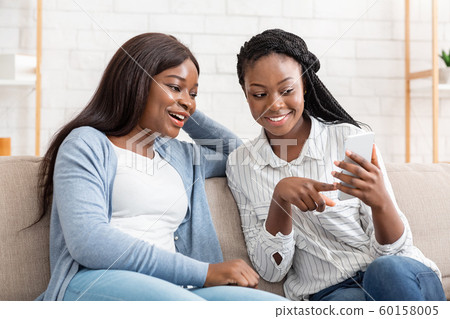 Happy African Girl Showing Message On Smartphone To Her Excited Happy African Girl Showing Message On Smartphone To Her Excited 60158005