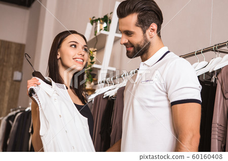 Young adult woman and man choosing wear in fashionable boutique 60160408