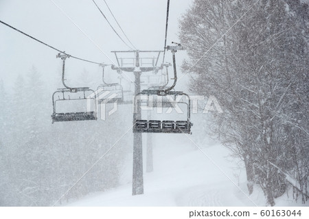 Ski lift in falling snow 60163044