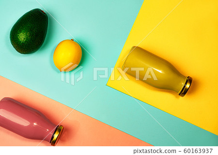 Bottles of multicolored juices or smoothies, lemon and avocado on yellow, pink coral and trendy mint 60163937