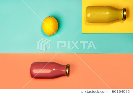 Bottles of multicolored juices or smoothies and lemon on yellow, pink coral and trendy mint green Bottles of multicolored juices or smoothies and lemon on yellow, pink coral and trendy mint green 60164055