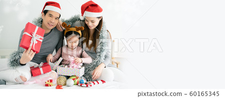 Asian family have father, mother and daughter with gray, pink casual wear and Santa hats 60165345