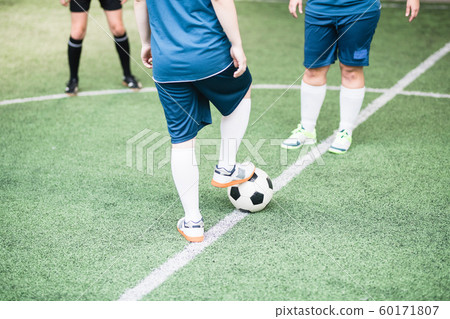 Female football player keeping foot on soccer ball in front of another girl Female football player keeping foot on soccer ball in front of another girl 60171807