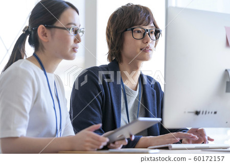 Young man and woman looking at computer monitor 60172157