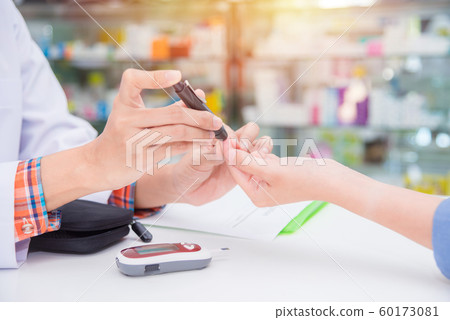 Hands of  Pharmacist checking patient blood sugar by glucometer  60173081