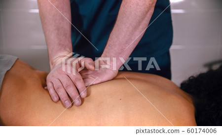 Chiropractic treatment - the doctor giving the patient a massage - softly pushing down on the lower back with hands 60174006