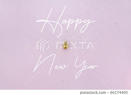 New Year celebration concept. Golden Christmas ball, lettering and golden star sequins on pastel New Year celebration concept. Golden Christmas ball, lettering and golden star sequins on pastel 60174405