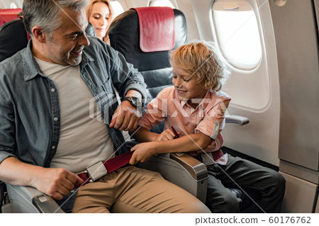 Smiling father is sitting near his son in plane Smiling father is sitting near his son in plane 60176762