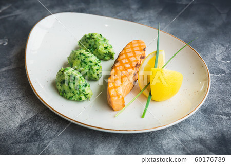 Dish with grilled salmon fish and lemon slices on grey. Close up view. Flat lay Dish with grilled salmon fish and lemon slices on grey. Close up view. Flat lay 60176789