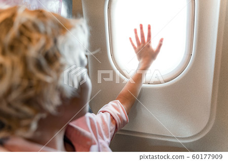 Smiling little boy looking at window in airplane 60177909