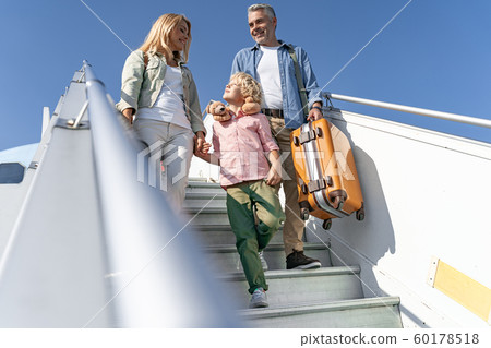 Happy mother looking at her little son on gangway of plane 60178518