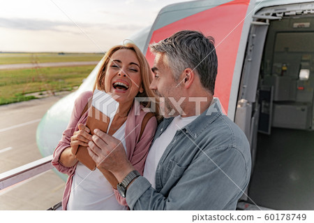 Happy couple in love standing near entrance to plane 60178749