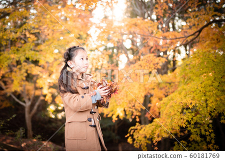 Girls playing with fallen leaves Girls playing with fallen leaves 60181769