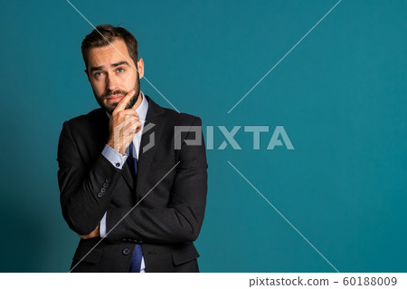 Serious thinking businessman looking around on blue background. Confused pensive face expressions. Handsome male model in corporate suit. Serious thinking businessman looking around on blue background. Confused pensive face expressions. Handsome male model in corporate suit. 60188009