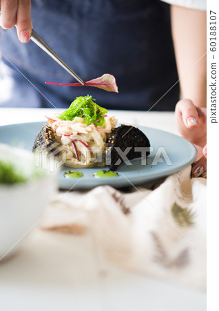 A chef is decorating a salad. Seaweed Salad 60188107