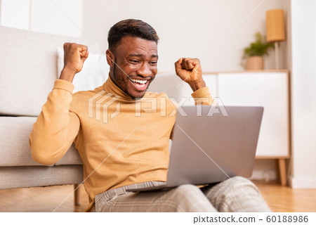 Afro Guy Holding Laptop Celebrating Business Success Sitting At Home 60188986