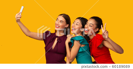 Three Millennial Girls Using Phone Making Selfie, Studio Shot, Panorama 60189089