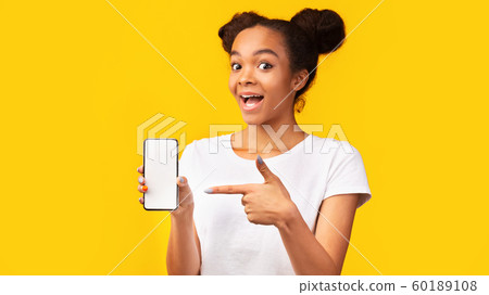 Amazed black girl pointing at blank white mobile screen 60189108