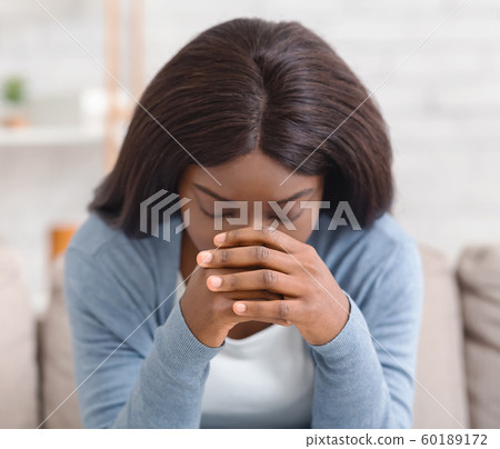 Depressed black woman sitting alone at home, feeling desperate 60189172