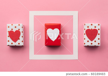 Handmade wrapped gift boxes, red hearts on pink background 60189483