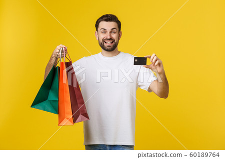 portrait of smiling couple holding shopping bags and credit card isolated on yellow background. portrait of smiling couple holding shopping bags and credit card isolated on yellow background. 60189764