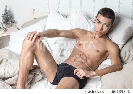 Young handsome man rest in bed. Sexy naked guy is 60189868