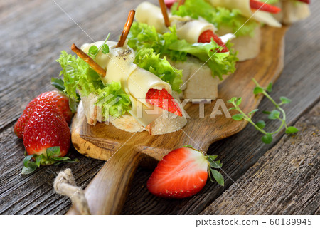 Canapes with delicious cheese rolls and strawberries on Italian ciabatta bread with lettuce leaves Canapes with delicious cheese rolls and strawberries on Italian ciabatta bread with lettuce leaves 60189945