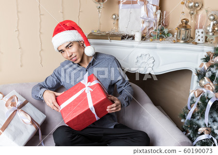 Young man in santa's hat sitting on couch near Young man in santa's hat sitting on couch near 60190073
