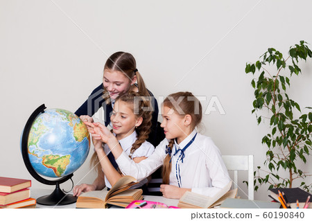 three girls of the school with books for studying sit at the desk in the class three girls of the school with books for studying sit at the desk in the class 60190840