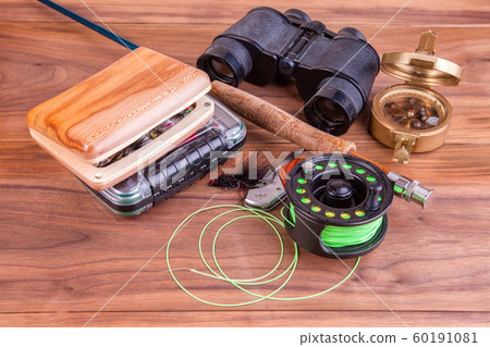 fly fishing rod with a coil and flies lie on old, wooden boards fly fishing rod with a coil and flies lie on old, wooden boards 60191081
