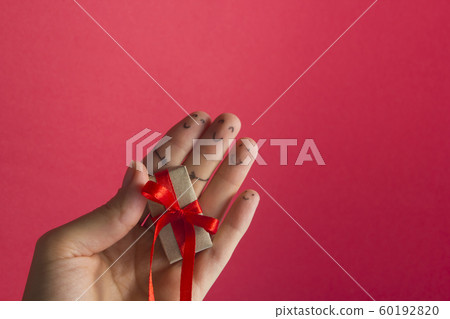 Funny fingers faces present gift box against red background with copy space for text. Happy family celebrating concept for Christmas or New Years day 60192820