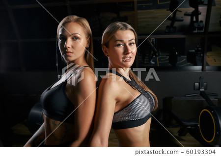 Brutal fitness two female friends with a muscular in the gym. Sports and fitness - concept of healthy lifestyle. Fitness woman in the gym. Brutal fitness two female friends with a muscular in the gym. Sports and fitness - concept of healthy lifestyle. Fitness woman in the gym. 60193304