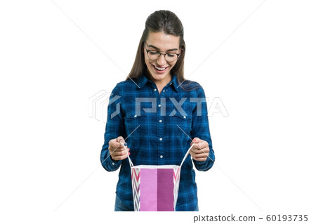 Surprised young woman in glasses and casual shirt looks in shopping bag, white background isolated Surprised young woman in glasses and casual shirt looks in shopping bag, white background isolated 60193735