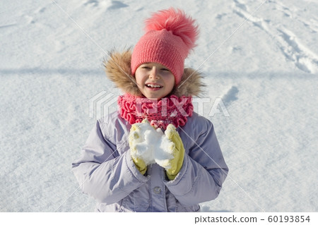 Winter outdoor portrait of child girl smiling and playing with snow, bright sunny winter day 60193854