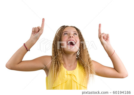 Happy blonde with curly hair, teen girl pointing her index finger up, indicating copy space on white blank wall for your content or information, isolated Happy blonde with curly hair, teen girl pointing her index finger up, indicating copy space on white blank wall for your content or information, isolated 60194186
