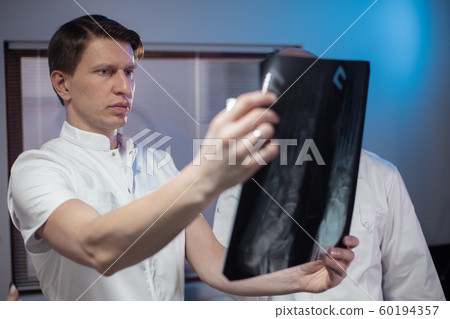 Three doctors look at an x-ray photo of a patient together 60194357