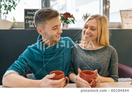 Young happy couple in love in cafe, young man and woman together smile hugging drink coffee tea 60194844