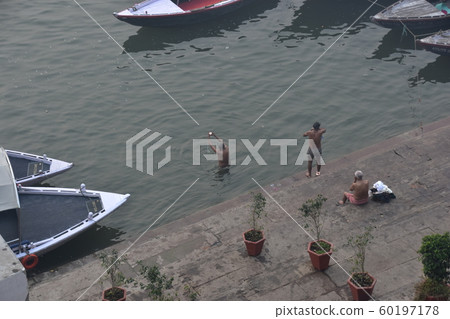 一名印度人在印度世界遺產恒河中沐浴,一條小船停泊 一名印度人在印度世界遺產恒河中沐浴,一條小船停泊 60197178