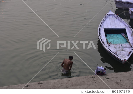 一名印度人在印度世界遺產恒河中沐浴,一條小船停泊 一名印度人在印度世界遺產恒河中沐浴,一條小船停泊 60197179