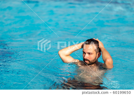 man is swimming in the swimming pool with spray on the face with dramatic effect. Rest, travel concept. man is swimming in the swimming pool with spray on the face with dramatic effect. Rest, travel concept. 60199650