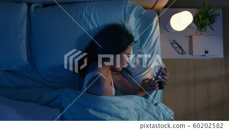 woman use smartphone on bed 60202582